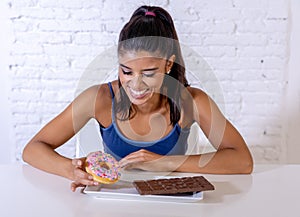 Portrait of young happy woman eating delighted chocolate bar and donuts