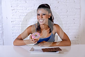 Portrait of young happy woman eating delighted chocolate bar and donuts