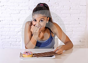 Portrait of young happy woman eating delighted chocolate bar and donuts