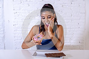 Portrait of young happy woman eating delighted chocolate bar and donuts