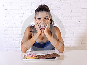 Portrait of young happy woman eating delighted chocolate bar and donuts