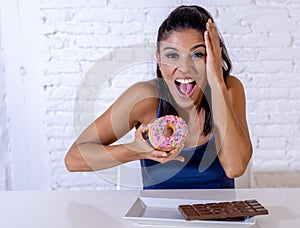 Portrait of young happy woman eating delighted chocolate bar and donuts