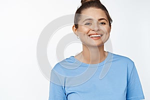 Portrait of young happy woman smiling at camera, wearing blue tshirt, white background