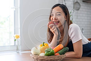 Portrait of young happy woman wearing appron standing in the kitchen room, prepares cooking healthy food from fresh