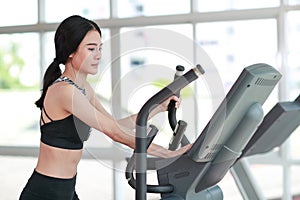 Portrait of young healthy and sporty woman using exercise machine in gym