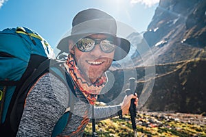 Portrait Young hiker backpacker man in sunglasses smiling at camera in Makalu Barun Park route during high altitude