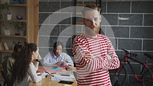 Portrait of young hipster male entrepreneur smiling and looking at camera while his colleagues working at modern loft