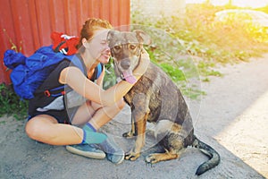 Portrait young hipster woman with backpack kissing dog outdoors Happy pet and attractive girl playing fun Positive human