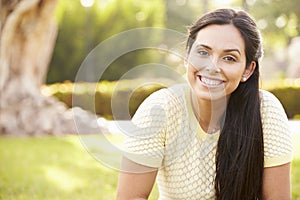 Portrait Of Young Hispanic Woman Sitting In Park