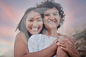 Portrait of a young hispanic woman spending the day at the beach with her elderly mother. Mixed race female and her