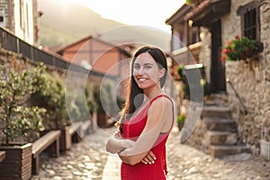 Portrait of young hispanic woman standing with crossed arms. She is in a rural town during sunset.