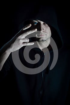 Portrait of a young hooded man with blue eyes making a bad gesture with his hand