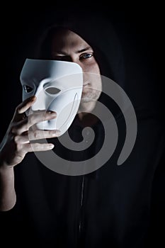 Portrait of a young hooded man taking off his mask, concept for being true and authentic