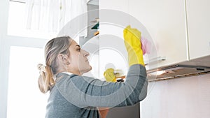 Portrait of young housewife washing kitchen wooden cupboards