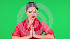 Portrait of young Indian girl with red bindi dot in national classic red sari looking down. Brunette with long hair and