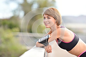 Portrait of young jogger woman with smartphone on her arm