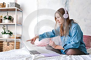 Portrait young joyful woman in home clothes, at laptop studying online or