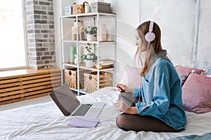 Portrait young joyful woman in home clothes, at laptop studying online or