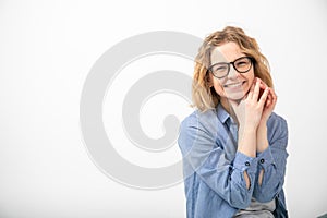 Portrait of young joyous attractive woman sit looking at camera, folding hands near face on white background. Emotions.