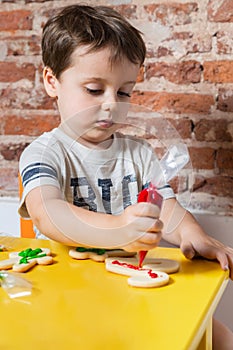 Portrait of young kid making cookies at home over yellow table