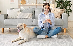 Portrait of young lady with her dog using mobile phone