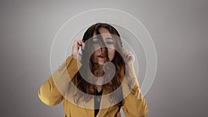 Portrait of a young lady listening to music by headphones and dancing on white background in slowmo