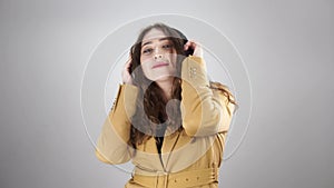 Portrait of a young lady listening to music by headphones and energy dancing on white background