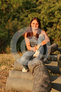 Portrait of a young lady sitting on a log