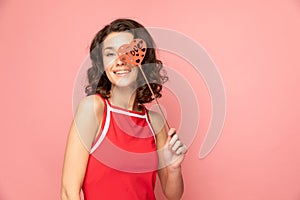 Portrait of young lady stands on pink background with heart shapped decoration