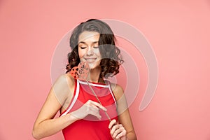 Portrait of young lady stands on pink background with heart shapped decoration