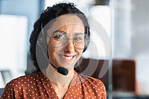 Portrait of a young Latin American woman in a headset. Call center He looks at the camera, smiles