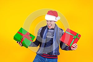 Portrait of young Latin man holding Christmas gift box on a yellow background in Mexico Latin America