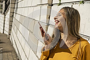 Portrait of a young Latin woman giving a funny message with her cell phone. Technology and communications concept