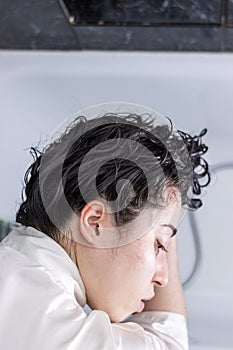 portrait of a young latin woman washing her hair with the shower at home to relax and keep her hair clean