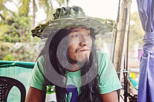 Portrait of young latino long hair man with handmade palm leaf hat