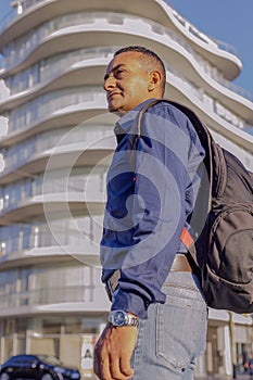 Portrait of young latino man with a backpack in a city