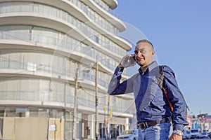 Portrait of young latino man in a city talking on a mobile phone with copy space