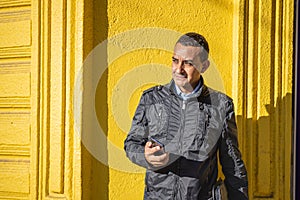 Portrait of a young latino man over a yellow wall with copy space