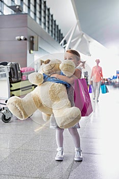 Portrait of young little girl holding her big teddy bear in airport
