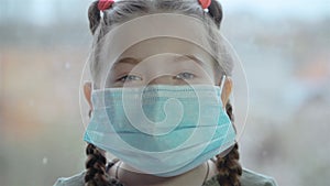 Portrait of young little girl wearing protective mask on window background for saving health and safety life