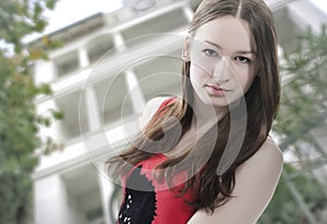 Portrait of young long hair teen girl with white building background