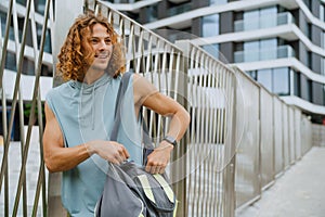 Portrait of young long-haired athletic man zipping up his bag