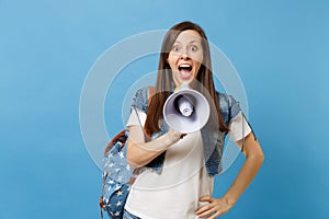 Portrait of young lovely amazed woman student in denim clothes with backpack holding electronic megaphone, shouting