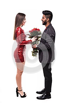 Portrait of a young lovely asian couple kissing while standing and holding flower bouquet over white background