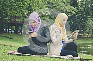 Portrait of young lovely pleasant mix ethnic woman sitting on grass at summer green park and having a discussion