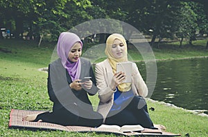 Portrait of young lovely pleasant mix ethnic woman sitting on grass at summer green park and having a discussion