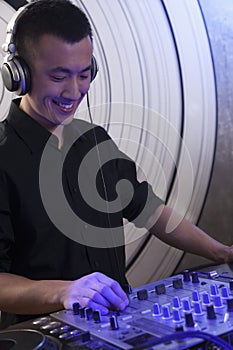 A portrait of a young male DJ playing music in a nightclub