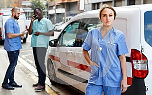 Portrait of young male and female paramedicals near ambulance car