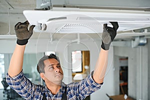 Portrait of young male indian technician repairing air conditioner. Air conditioner repairs.