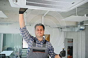 Portrait of young male indian technician repairing air conditioner. Air conditioner repairs.